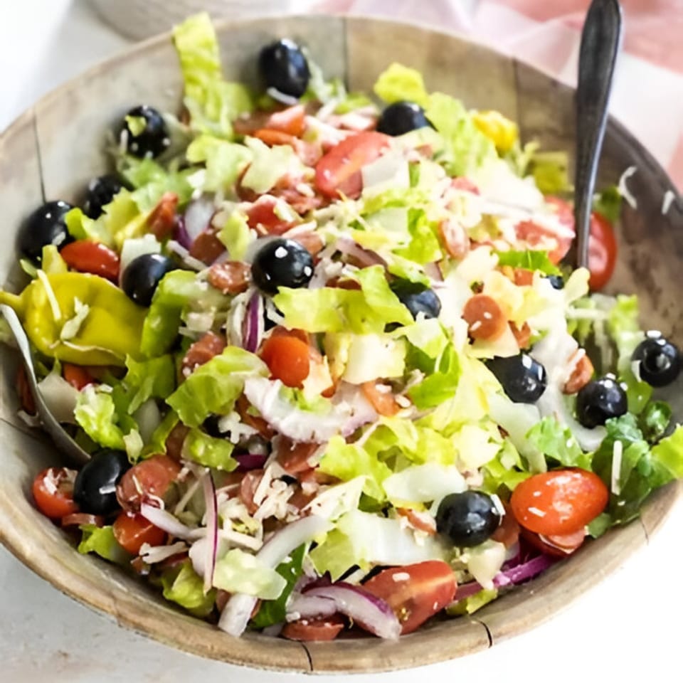A large wooden bowl filled with Gina's Pizzeria house salad, featuring lettuce, tomatoes, olives, and peppers.