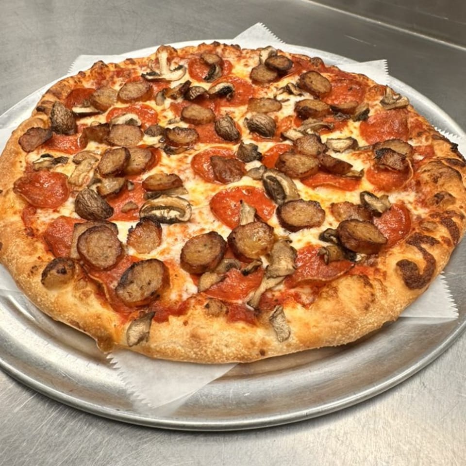Gina's Pizzeria pepperoni, sausage, and mushroom pizza on a metal tray.